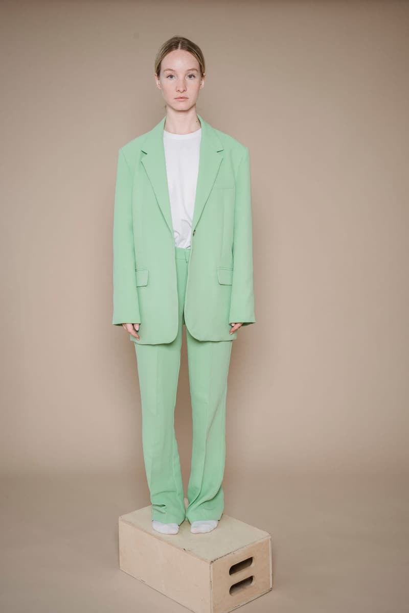 Woman in a mint green blazer and trousers standing on a wooden box